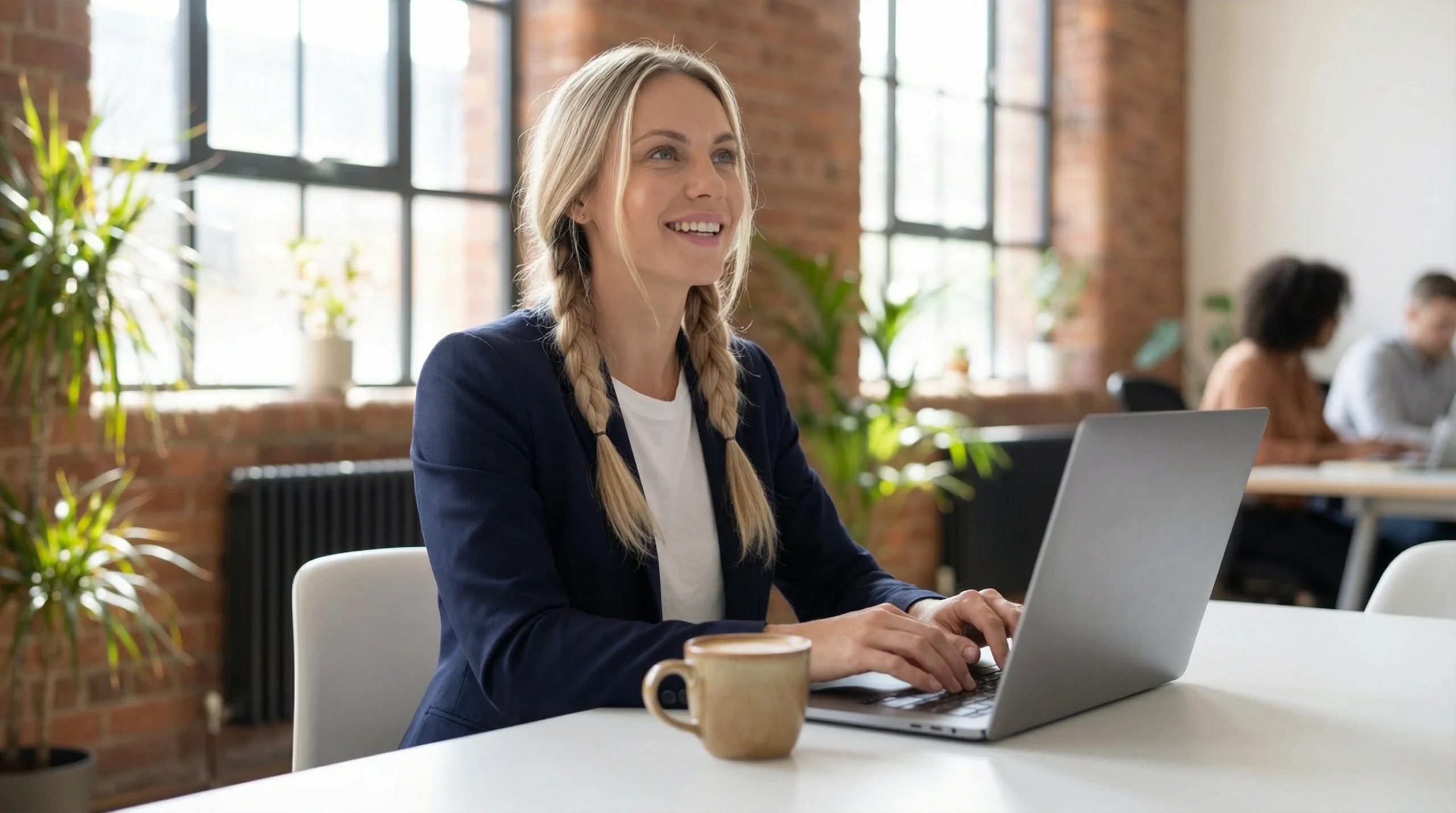 Anna Sinclair-Sorenson working at laptop in modern office, leading See My Goals with purpose and vision